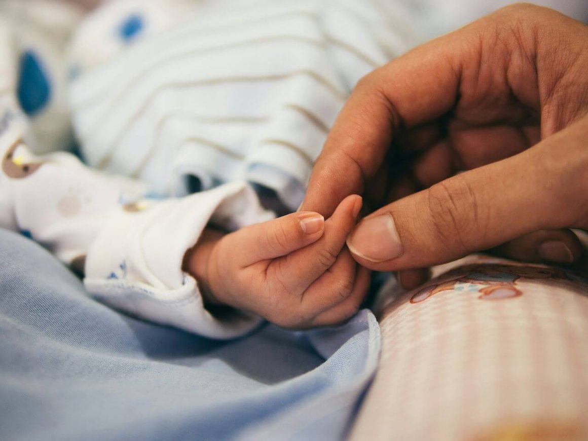 pregnancy due date calculator :  a picture of an infant's hands on a woman's 